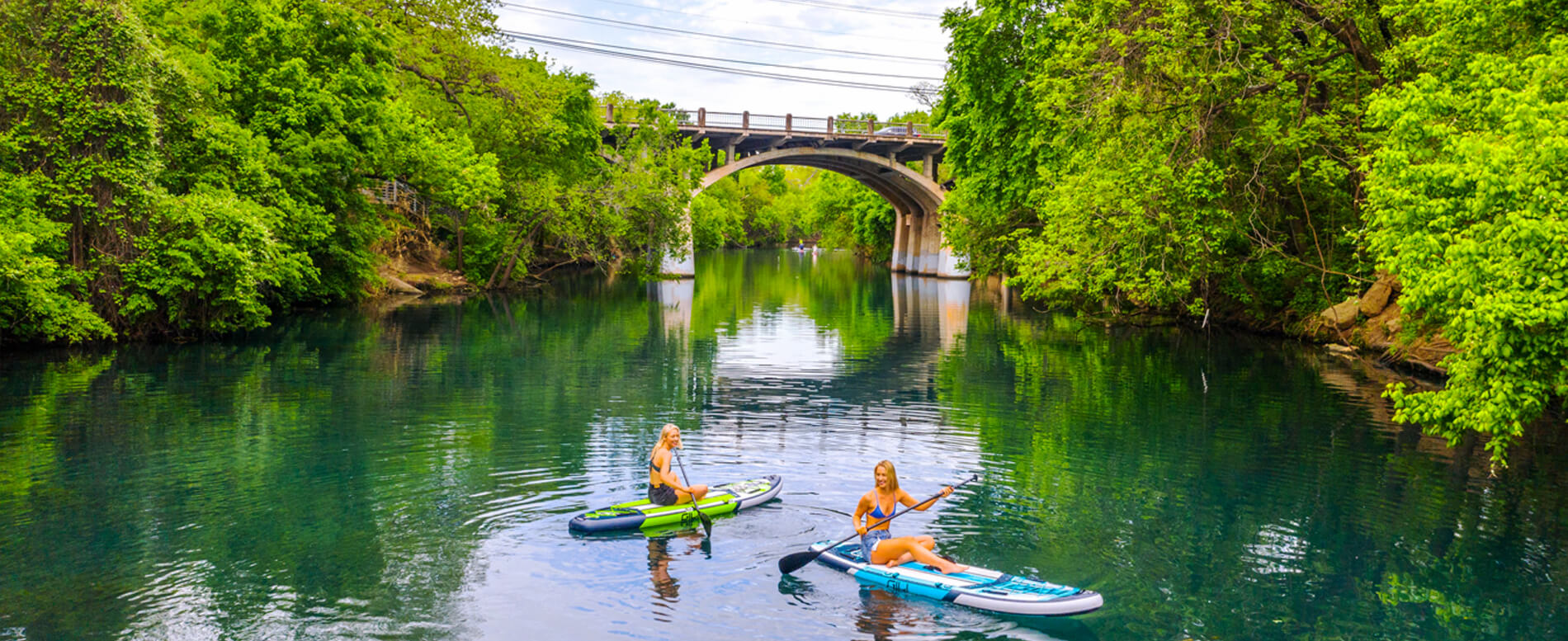 two women paddle boarding on river
