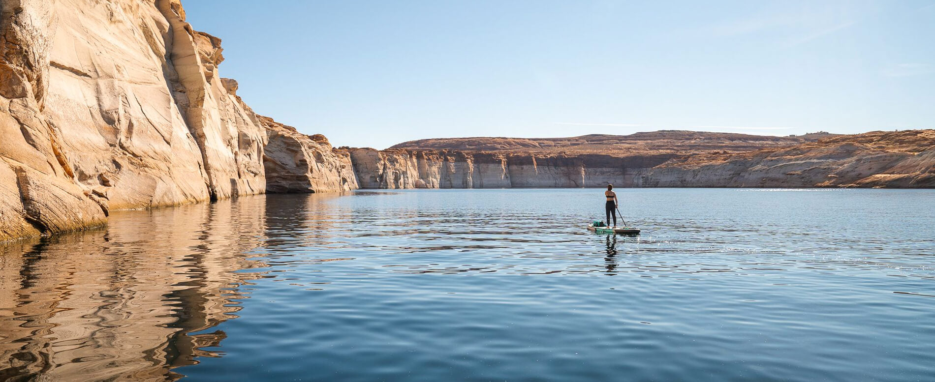 Woman paddle boarding on a flat water lake in antelope canyon