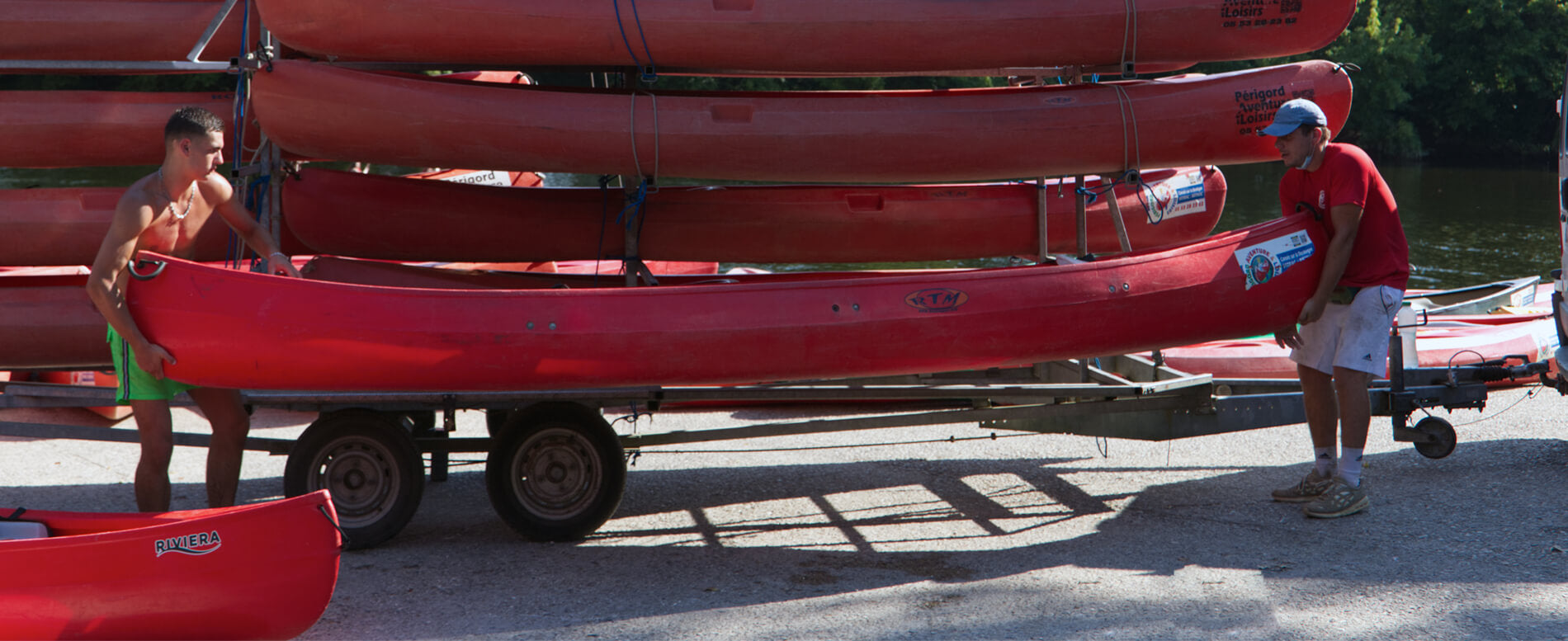 Two men transporting a red kayak