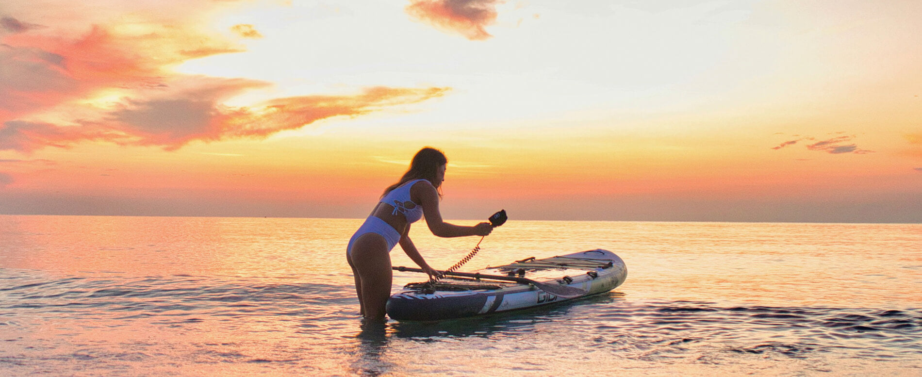 Woman paddle boarding in the ocean at night fall